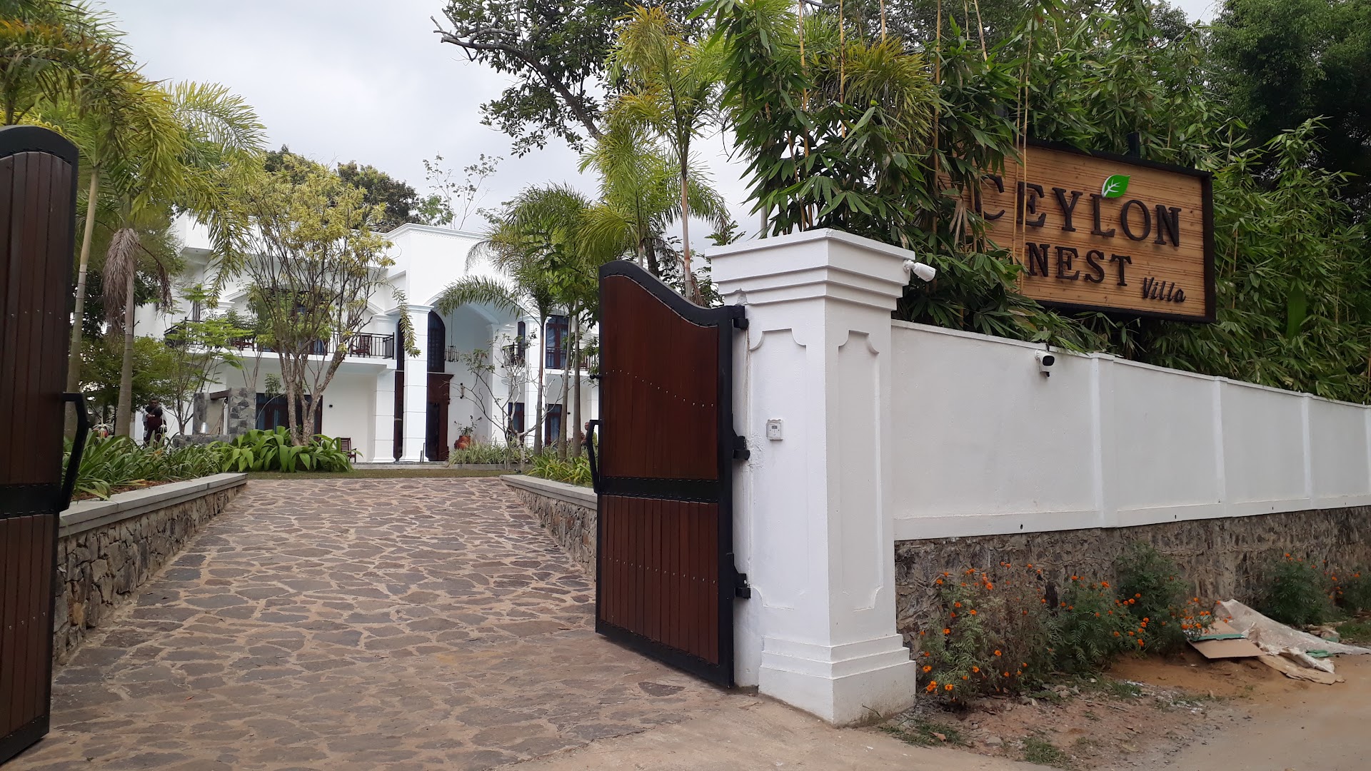 Open timber gates leading along a stone drive to the white villa