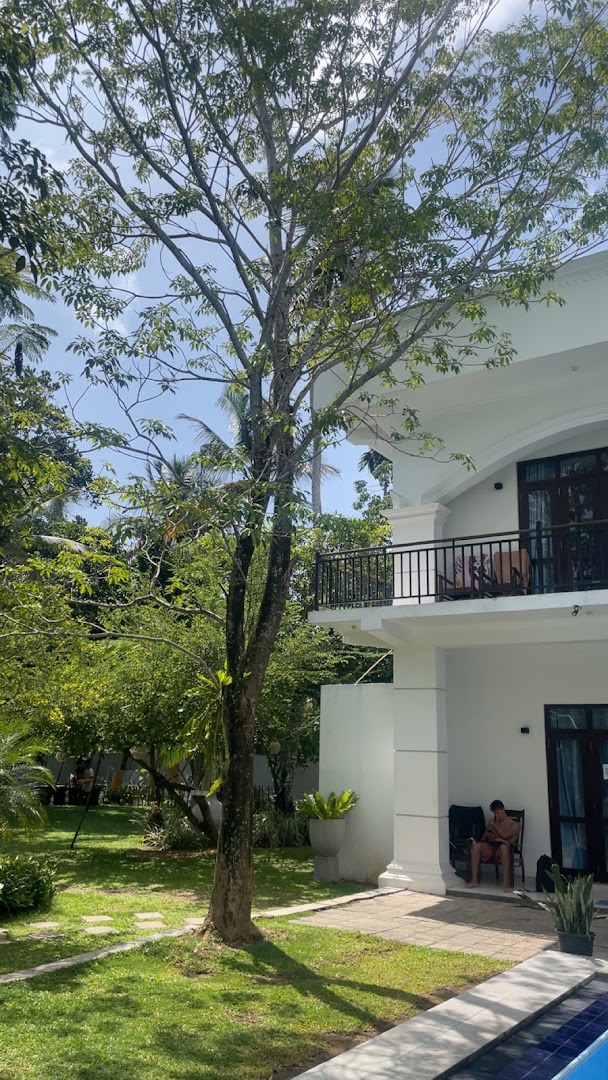 White villa beside mature trees and a green lawn