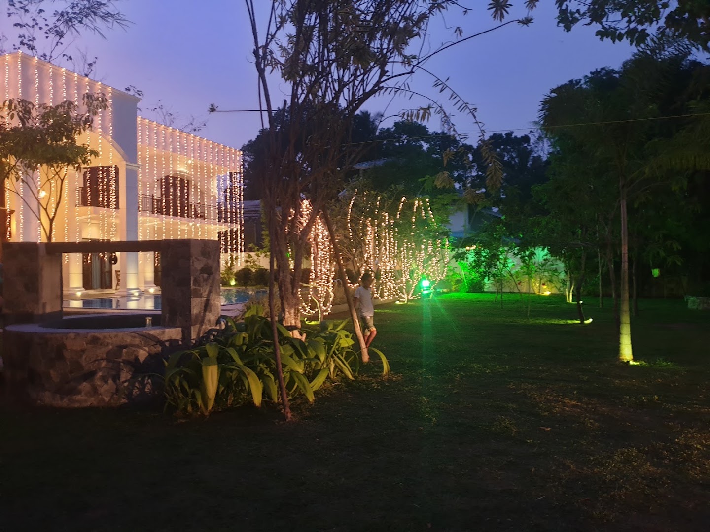 Villa and garden illuminated with warm lights at dusk